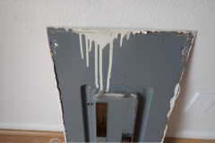 This electrical panel cover was sealed to the wall with paint. The paint job was sloppy enough for paint to run into the panel.